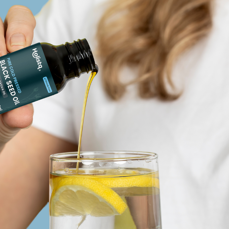 Holistq cold-pressed black seed oil poured into lemon water